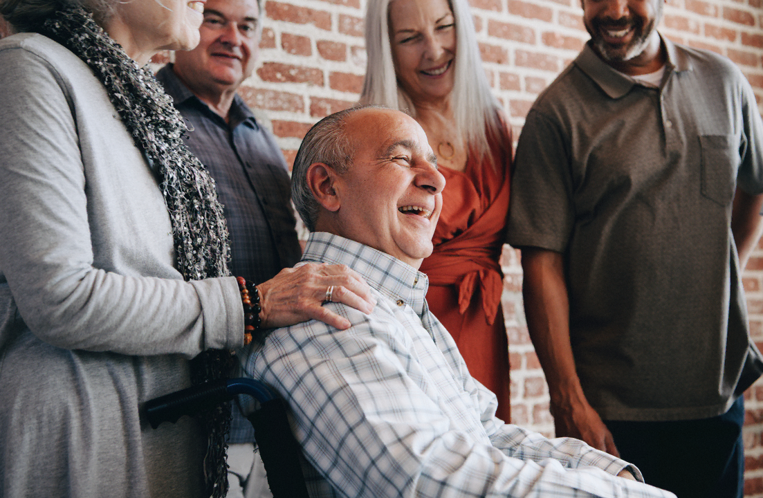 Happy man sitting in a chair, surrounded with friends